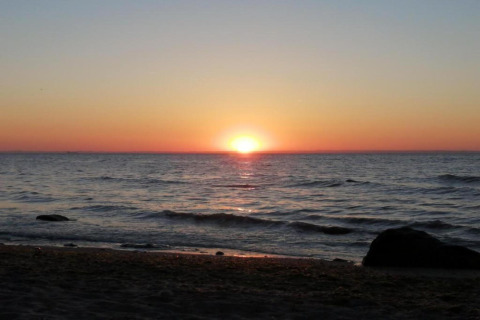 Zonsondergang boven de zee vanaf het strand bij de hut ‘Platz im Grünen 2’ in Duitsland.