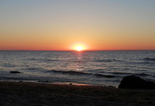 Zonsondergang boven de zee vanaf het strand bij de hut ‘Platz im Grünen 2’ in Duitsland.