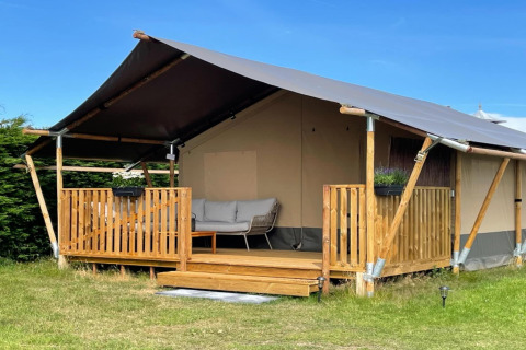 Photo of a luxury safari tent on Ameland with wooden deck, sofa seating, and peaceful surroundings.