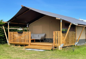 Photo of a luxury safari tent on Ameland with wooden deck, sofa seating, and peaceful surroundings.