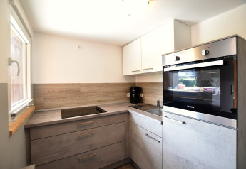 Modern kitchen with stovetop, oven and sink at Bungalow complex «Gänseblümchen 2» in Germany.