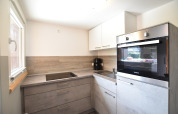 Cuisine moderne avec plaques, four et évier au complexe Bungalow «Gänseblümchen 2» en Allemagne.