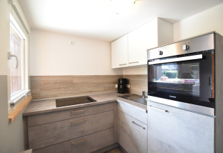Cocina moderna con placa, horno y fregadero en el complejo Bungalow «Gänseblümchen 2» en Alemania.