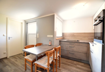 Heldere, moderne keuken in bungalowcomplex 'Gänseblümchen 2' met eettafel en vier stoelen in Duitsland.
