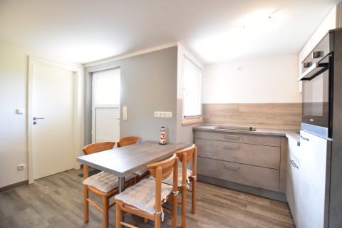 Cocina moderna y luminosa en el complejo Bungalow «Gänseblümchen 2» con mesa de comedor y cuatro sillas en Alemania.