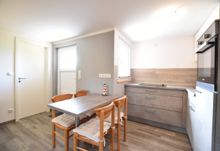 Cocina moderna y luminosa en el complejo Bungalow «Gänseblümchen 2» con mesa de comedor y cuatro sillas en Alemania.