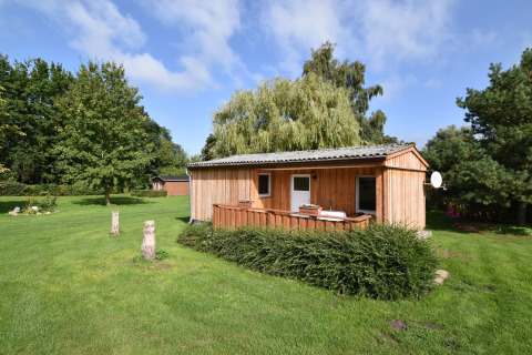 Cabaña de madera en jardín verde y soleado, complejo Bungalow Gänseblümchen 2 en Alemania.