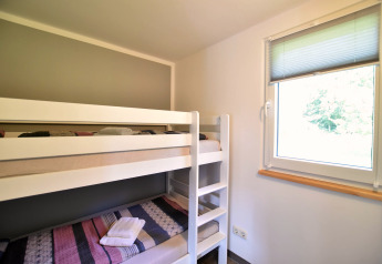 Lichte kamer met stapelbed en raam, genomen in bungalowcomplex «Gänseblümchen 2» in Duitsland.