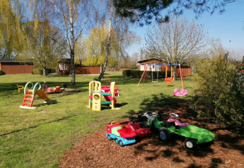 Aire de jeux extérieure au complexe Bungalow Gänseblümchen 2 en Allemagne avec balançoires et toboggan.