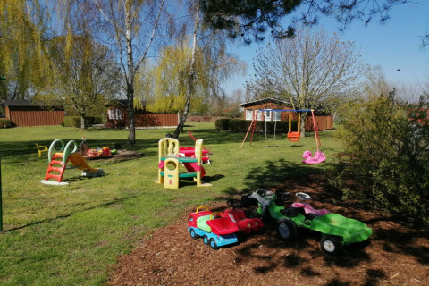 Parque infantil exterior en el complejo Gänseblümchen 2 en Alemania con columpios, tobogán y coches de juguete.