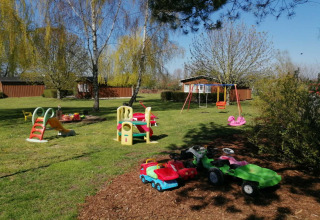 Parque infantil exterior en el complejo Gänseblümchen 2 en Alemania con columpios, tobogán y coches de juguete.