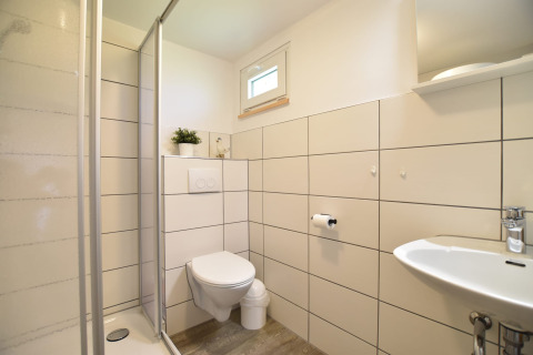 Moderne badeværelse i Bungalow-komplekset Gänseblümchen 2, Tyskland, med bruser, toilet og håndvask.