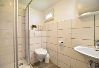 Baño moderno en el complejo de bungalows Gänseblümchen 2, Alemania, con ducha, inodoro y lavabo.