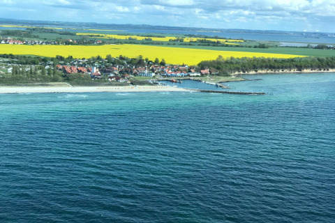 Vista costera desde el complejo de bungalows «Gänseblümchen 2» en Alemania, con mar, playa y campos amarillos.