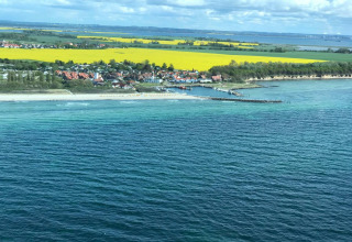 Vista costera desde el complejo de bungalows «Gänseblümchen 2» en Alemania, con mar, playa y campos amarillos.
