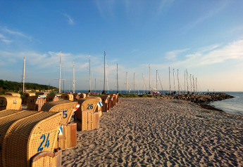 Plage avec chaises en osier et voiliers en arrière-plan près du complexe « Gänseblümchen 2 » en Allemagne.