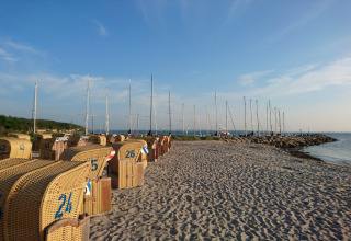 Playa con sillas de mimbre y veleros al fondo en el complejo de bungalows «Gänseblümchen 2» en Alemania.