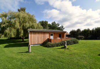 Houten bungalow bij Gänseblümchen 2 in Duitsland, omgeven door gras en bomen onder een blauwe hemel.