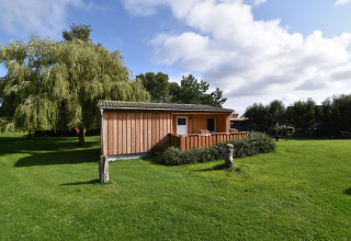 Bungalow in legno presso Gänseblümchen 2 in Germania, circondato da prato verde e alberi sotto il sole.