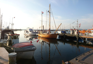 Barcos atracados junto al complejo de bungalós «Gänseblümchen 2» en Alemania bajo un cielo despejado.