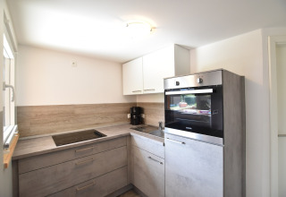 Cocina moderna en complejo Bungalow «Gänseblümchen 2» en Alemania, con gabinetes grises y horno empotrado.