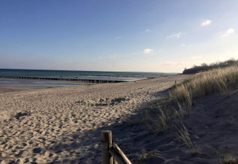Vue de la plage depuis le complexe de bungalows «Gänseblümchen 2» en Allemagne avec dunes et mer au loin.