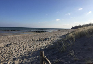 Vista de playa desde el complejo de bungalows «Gänseblümchen 2» en Alemania con dunas y mar al fondo.