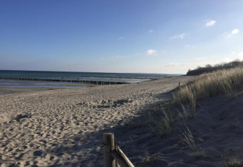 Vue de la plage depuis le complexe de bungalows «Gänseblümchen 2» en Allemagne avec dunes et mer au loin.