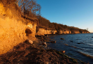 Sunlit coastal cliffs beside the sea near Bungalow complex ‘Gänseblümchen 2’ in Germany.