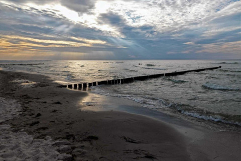 Alba sulla spiaggia con onde, sabbia e pennelli presso il complesso Gänseblümchen 2, Germania.