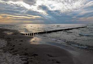 Amanecer en la playa con olas, arena y espigones en el complejo Gänseblümchen 2, Alemania.