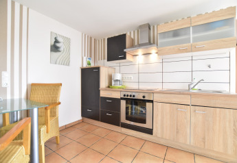 Bright modern kitchen of Bungalow complex Gänseblümchen 7 in Germany with wooden cabinets and dining area.