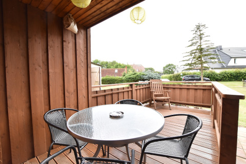 Wooden outdoor terrace with table and chairs at Bungalow complex Gänseblümchen 7 in Germany.