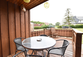 Wooden outdoor terrace with table and chairs at Bungalow complex Gänseblümchen 7 in Germany.