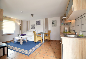 Espace lumineux au complexe Bungalow Gänseblümchen 7 en Allemagne, avec cuisine, canapé et salle à manger.