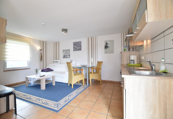 Espace lumineux au complexe Bungalow Gänseblümchen 7 en Allemagne, avec cuisine, canapé et salle à manger.