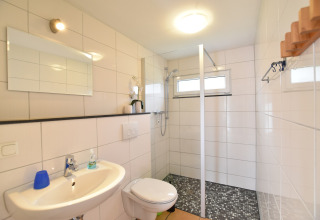 Modern bathroom with shower, toilet and sink in Bungalow complex «Gänseblümchen 7» in Germany.