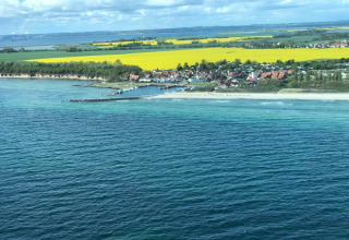 Aerial view of Bungalow complex «Gänseblümchen 7» by the sea with beach, fields, and village in Germany.
