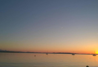 Beautiful sunset view from Bungalow complex ‘Gänseblümchen 7’ in Germany with boats on calm water.