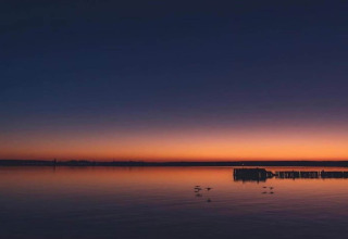 Sunset over the lake by Bungalow complex «Gänseblümchen 7» in Germany, calm water and a tranquil sky.
