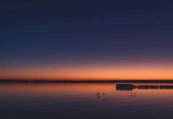 Coucher du soleil sur le lac près du complexe Bungalow «Gänseblümchen 7» en Allemagne, eau calme et ciel paisible.