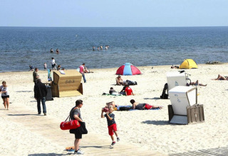 Des personnes profitent de la plage avec tentes et fauteuils confortables, typique d’un séjour glamping.
