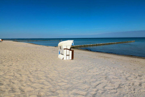 Beach scene with a beach chair at Bungalow complex Gänseblümchen 7 in Germany beneath a clear sky.