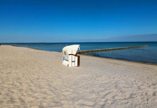 Beach scene with a beach chair at Bungalow complex Gänseblümchen 7 in Germany beneath a clear sky.