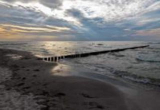 Sunset over the beach near Bungalow complex «Gänseblümchen 7» in Germany, showing dramatic cloudy sky.