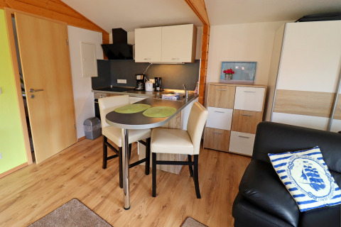 Modern cabin kitchenette with dining space and wood accents at Räuberkuhle Koserow in Germany.