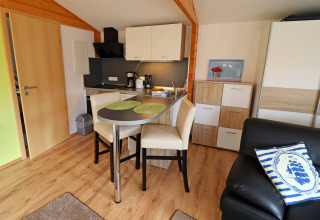 Modern cabin kitchenette with dining space and wood accents at Räuberkuhle Koserow in Germany.
