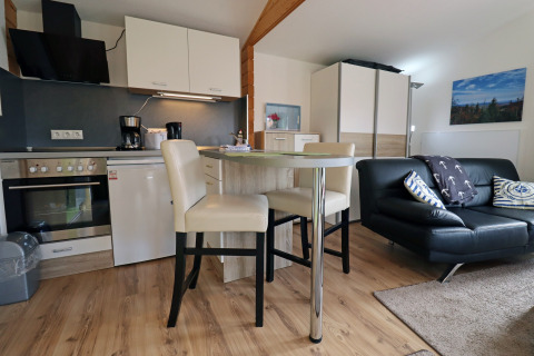 Modern cabin interior at Räuberkuhle Koserow, Germany, showing kitchen, dining table, and living area.