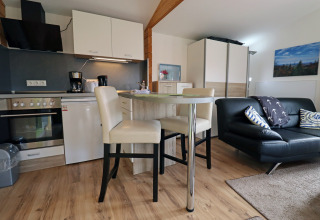 Modern cabin interior at Räuberkuhle Koserow, Germany, showing kitchen, dining table, and living area.