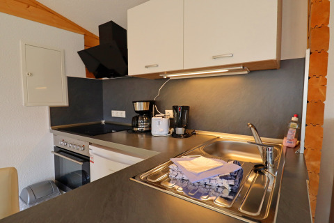Modern kitchen at Räuberkuhle Koserow in Germany with appliances, sink, dish soap, and folded towels.